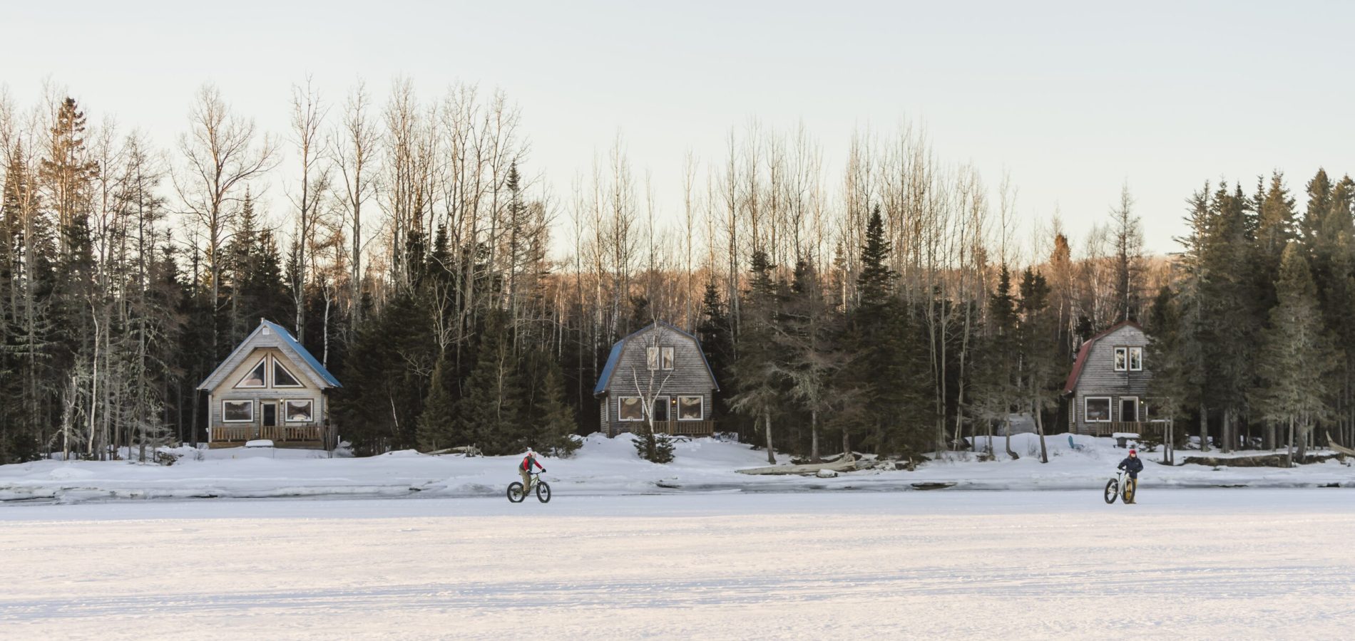 Deux vélos à pneus surdimensionnés sur la glace devant les chalets du bout du monde en hiver en Gaspésie.