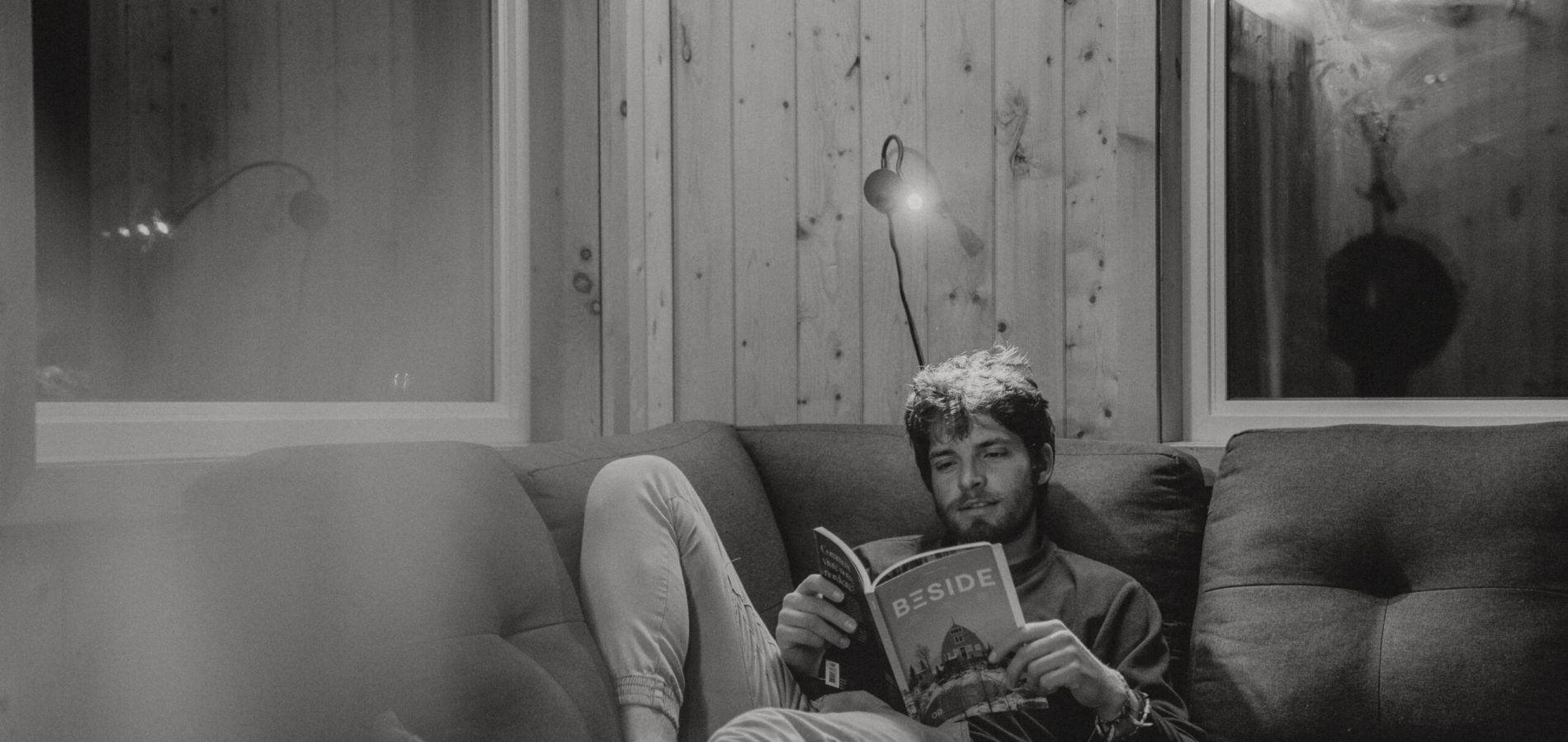 Un homme qui lit un livre à l'intérieur du confort de notre chalet à Gaspé.