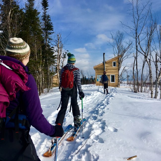 Des amis en ski de fond et en raquette de neige se dirigent vers un chalet à Gaspé.