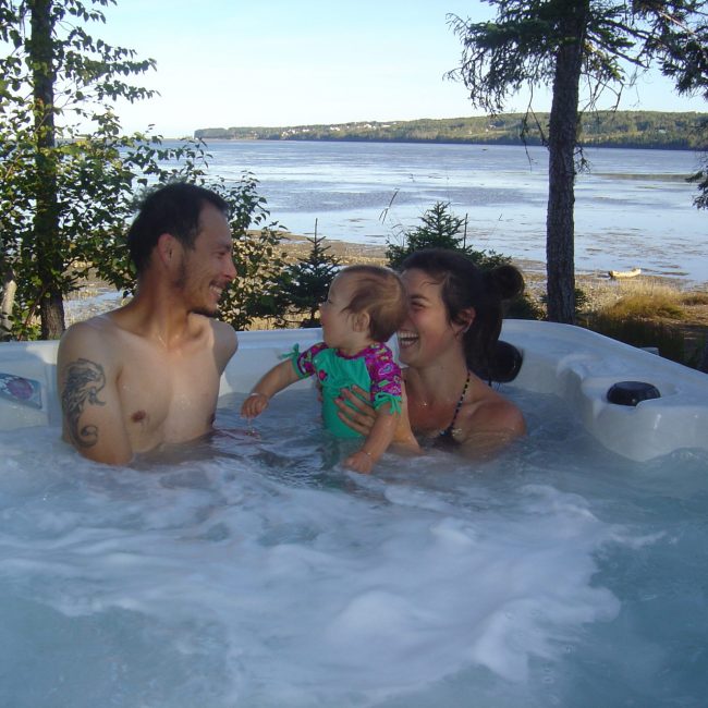 Une femme, un homme et un bébé s'amusant dans le spa du chalet.