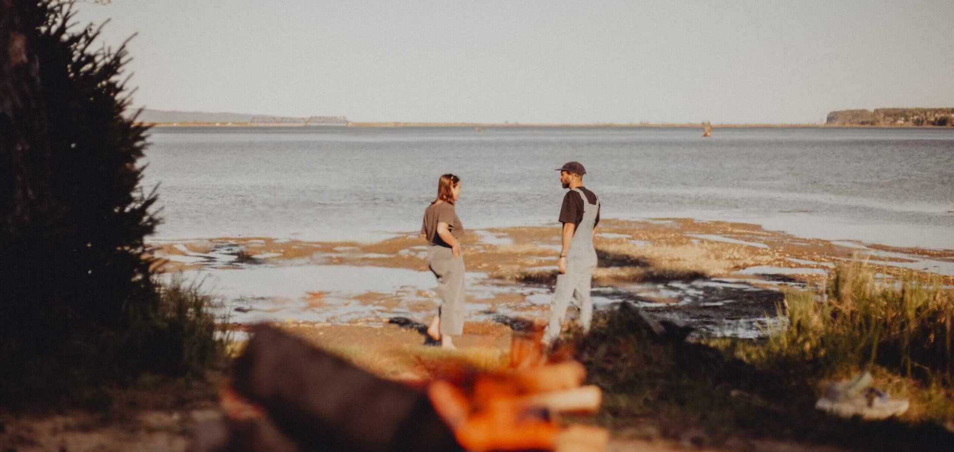Couple discute sur le bord de l'eau avec le parc Forillon et la plage de haldimand derrière.